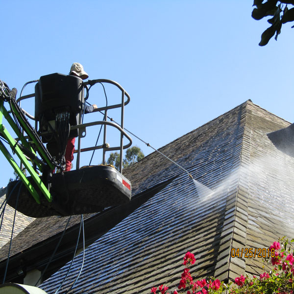 Technician using a lift to clean a high roof surface