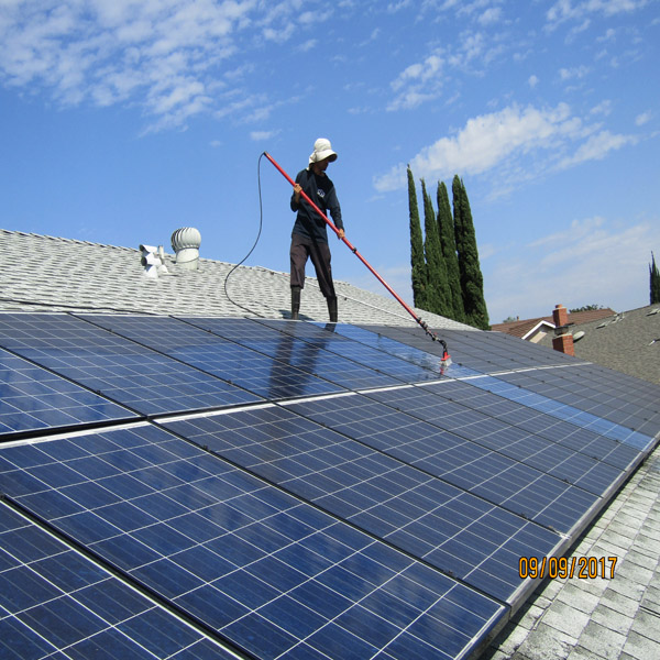 Technician cleaning solar panels on a residential roof